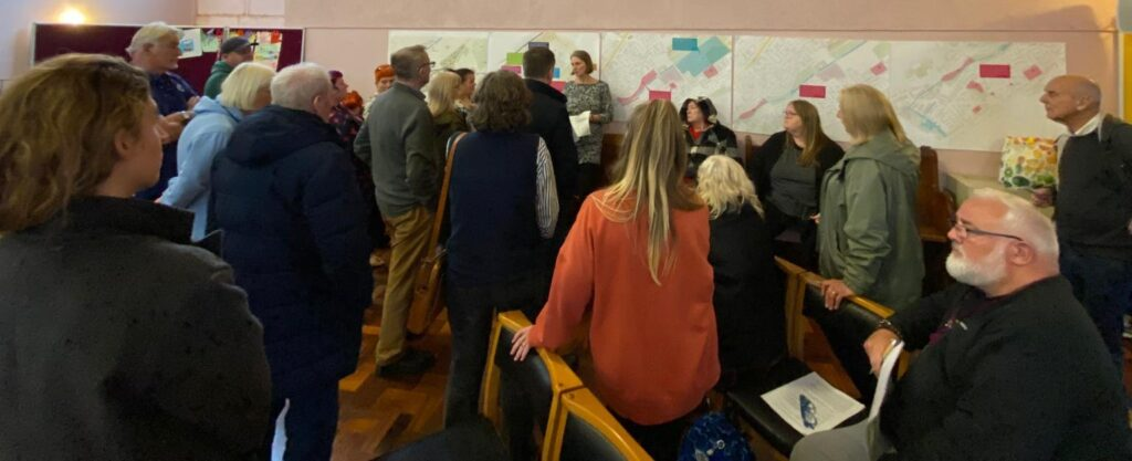 Ancoats residents in a meeting room looking at local area plans pinned to the wall